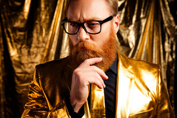 Elegant man in golden suit with glasses contemplating in a glamorous golden setting, exuding...