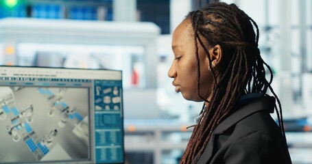 Photovoltaics factory programmer coding on PC to improve solar panels efficiency. African american...