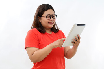 Fototapeta premium Smiling busy young asian business woman manager using tablet computer, happy business woman executive looking at tab device analyzing finance trading market data working standing over white background