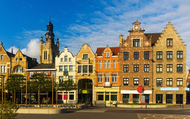 Scenic view of summer cityscape of Roeselare overlooking belfry of Saint Michael Church rising above typical Flemish style townhouses on central Grote Markt square on sunny day, West Flanders, Belgium