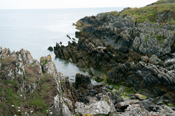 A rocky shoreline with a small body of water in the foreground
