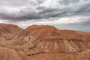A rocky, barren landscape with a cloudy sky in the background