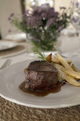 Gourmet gastronomy. Wedding main course. Closeup view of grilled loin tournedo with a red wine sauce and potatoes on the table with a beautiful glassware and tableware arrangement