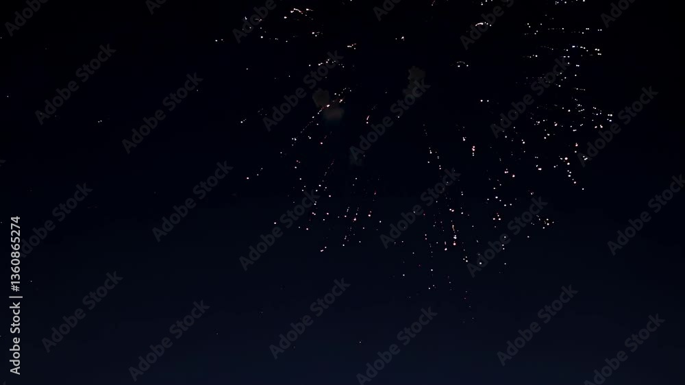 Poster aerial video captures a vibrant red firework exploding against a dark sky, shot from a low angle, em