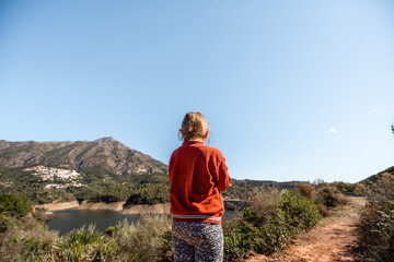 Naklejka premium Female caucasian adult enjoys scenic mountain view near reservoir under clear sky