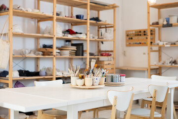 Pottery art studio with wooden shelves and table with necessary tools on it