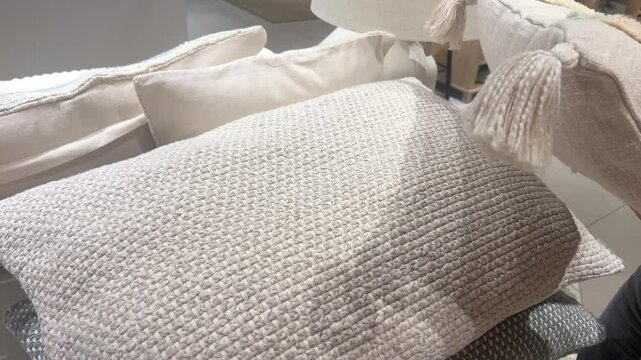 Woman chooses decorative pillows with floral embroidery in home decor store