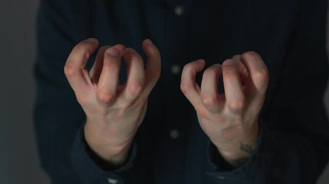 A man clenches his fists in anger.
A man waves his fists.
Behavior of an aggressive person.
A man in a blue shirt is angry and freaking out