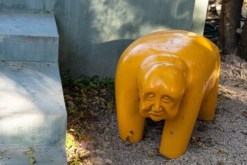 Yellow elephant statue with human face standing near concrete steps in merida, mexico