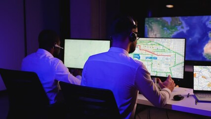 Two dispatchers tracking cargo routes on digital maps - Powered by Adobe