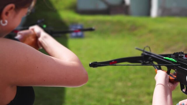 Crossbow shooting and archery at the shooting range, women and men practicing with arbalest at shooting gallery, compound bow training, aiming the target with arbalest at archery range, bow and arrows