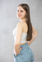 Young smiling woman in jeans and top poses in studio