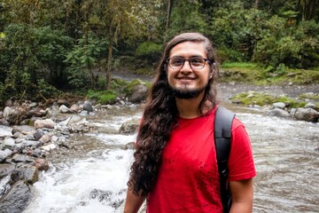 latino male traveling in the wilderness. Hispanic traveler in a mountain. Happy hiker in front of a lagoon