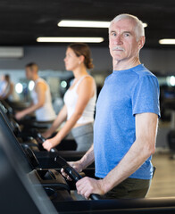 Obraz premium Portrait of elderly man running on treadmill in gym