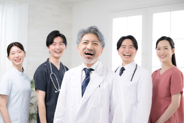カッコイイグレイヘアの医者と複数のドクターのイメージ　笑顔のカメラ目線　大笑いで成功などのイメージ
