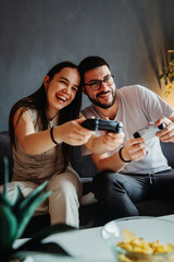 Young caucasian couple smile and play video games on joystick 