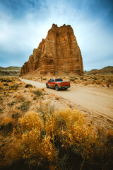 Red Pickup Truck on a Scenic Desert Road in Cathedral Valley, Capitol Reef National Park in USA, Temple of the Sun on the background