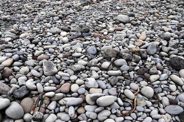 Smooth gray pebbles covering Icelandic shore in a cloudy day