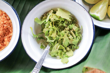 Fresh chopped green coriander in vintage metal white bowl on banana leave. Ingredient for food.