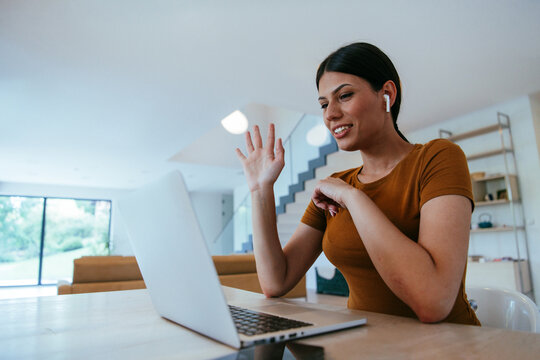Woman sitting in living room using laptop looking at cam talk by video call with business friend relatives, head shot. Job interview answering questions