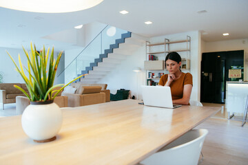 Woman sitting in living room using laptop looking at cam talk by video call with business friend...