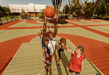 Black basketball player jumping to score goal and his team at outdoor court, above view