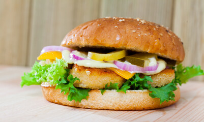 Delicious burger with chicken nuggets, cheese, pickled cucumber, fresh onion and lettuce..