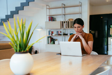 Woman sitting in living room using laptop looking at cam talk by video call with business friend...