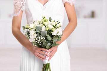 Bride with beautiful wedding bouquet on light background, closeup
