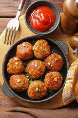 Tasty meatballs with green onion in baking dish served on wooden table, flat lay