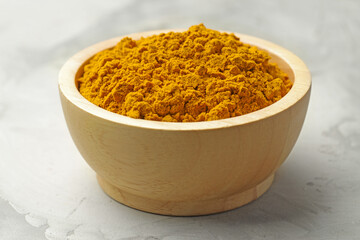 Turmeric powder in bowl on light table, closeup