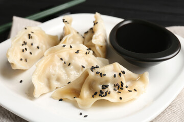 Delicious gyoza dumplings with sesame seeds served on table, closeup