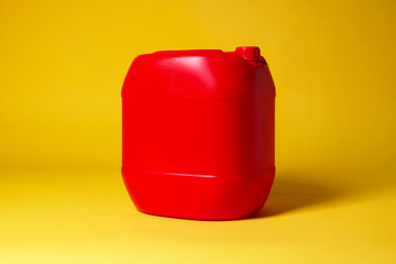 One red plastic canister on yellow background, space for text