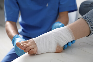 Doctor bandaging patient's foot in clinic, closeup
