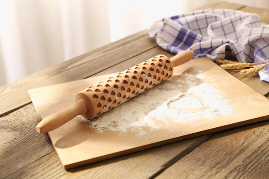Rolling pin, flour, spikes and napkin on wooden table indoors, closeup