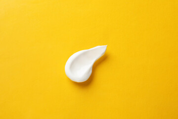 Smear of body cream on orange background, top view