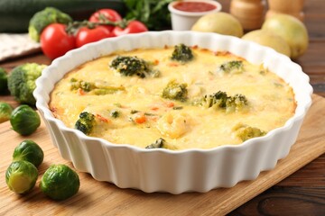 Delicious vegetable casserole and ingredients on wooden table, closeup