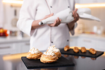 Professional pastry chef making desserts at table in kitchen, closeup