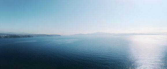 Coastal panorama serene sea, distant mountains, clear sky