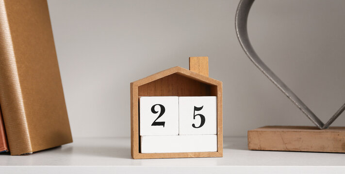 Shelf with books, calendar and stylish decor, closeup