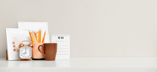 Comfortable workplace with picture frames, alarm clock and stationery near color wall