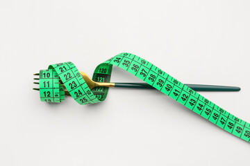 New measuring tape and fork on light background