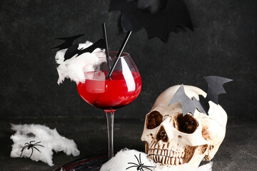 Glass of tasty Margarita cocktail, skull and decorations for Halloween on black background