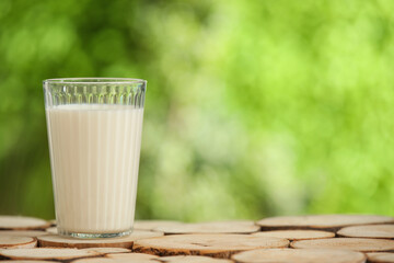 Glass of fresh milk on wooden table outdoors
