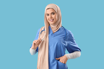 Muslim medical intern with stethoscope on blue background