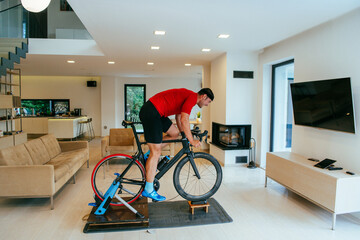 A triathlete riding a triathlon bike on a machine simulation in a modern living room