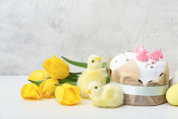 Tasty Easter cake with chicks and yellow tulips on white background