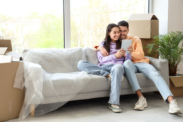 Fototapeta premium Young couple using tablet computer in room on moving day