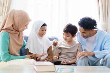 Asian muslim family with father, mother, son, and daughter are sitting in the cozy living room and have a talk together.