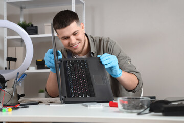 Male technician repairing laptop at table in service center